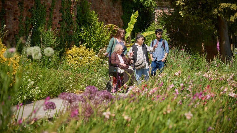 A group of four people, one of which is a wheelchair user, admiring the garden at Tredegar House, South Wales